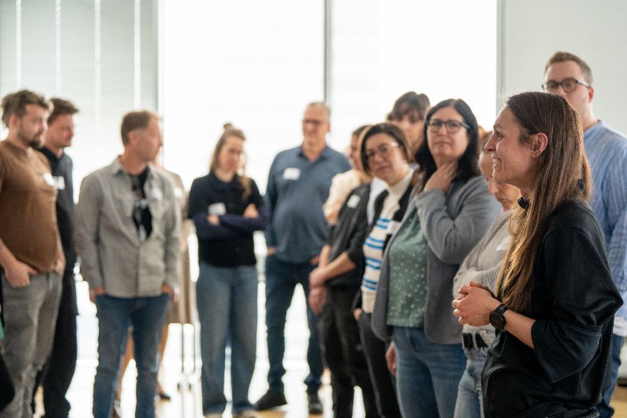 In einem Halbkreis stehende Personen in einem Raum